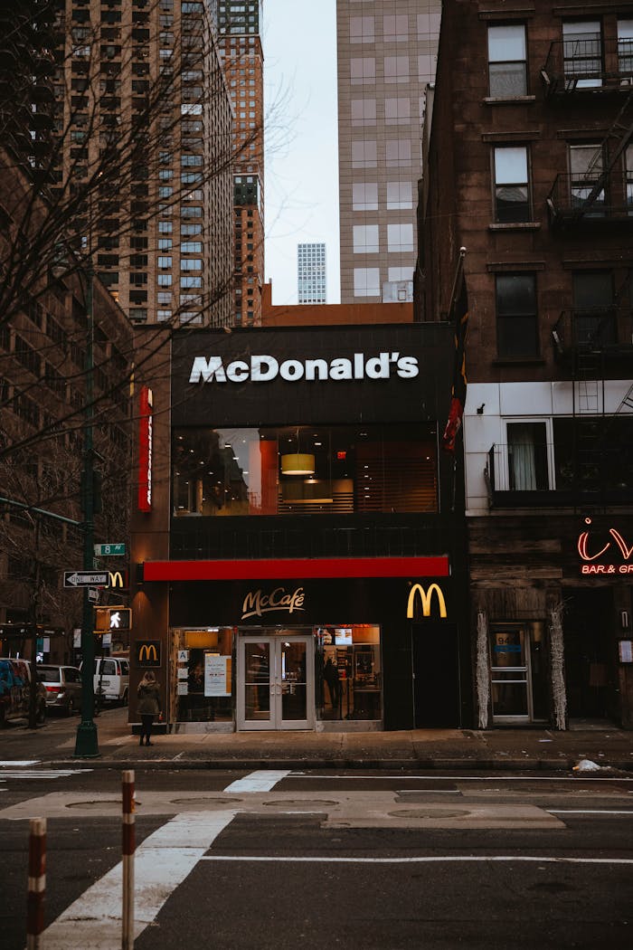 Front view of a McDonald's restaurant on a busy city street with surrounding buildings.